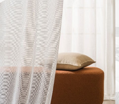 Sheer curtain and rust velvet ottoman