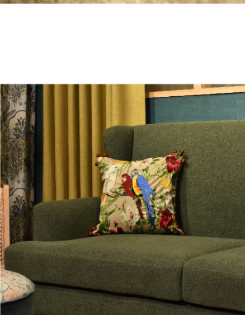 Green sofa with parrot embroidered cushion